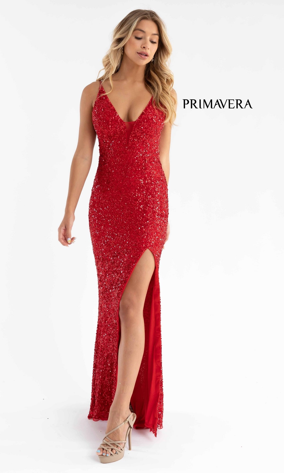 A woman in the Primavera Dark Sequin Long Prom Dress 3792D, featuring a strappy open back and thigh-high slit, paired with beige heels, stands against a plain white background.